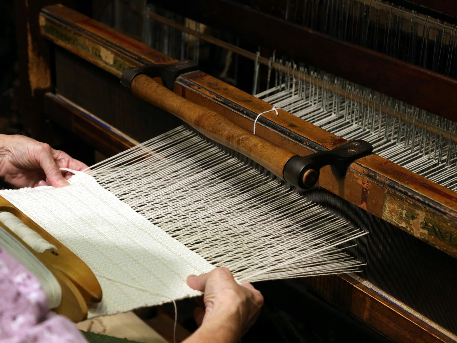 A handloom mid-weave, warp threads stretched across the frame