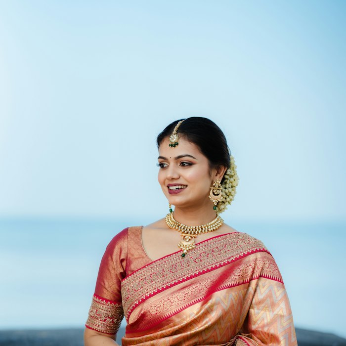 Campaign still of a red and gold silk saree by the sea